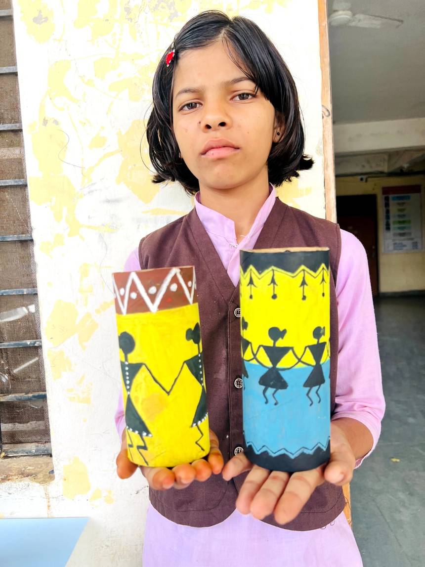 A student showing hand painted craft items made during an art activity