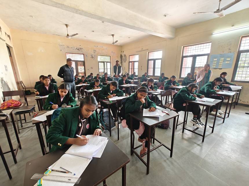 Students writing at individual desks during a supervised examination