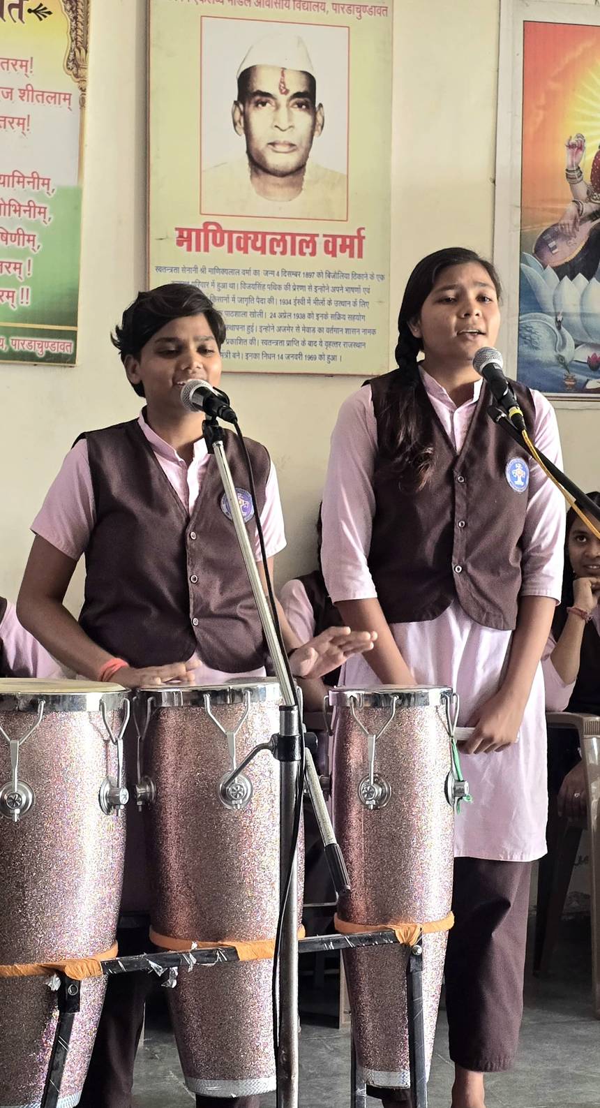 Students singing at the microphone with drums during a cultural programme