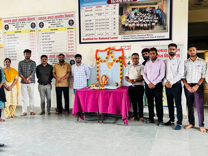 Staff beside the school notice board displaying examination result charts