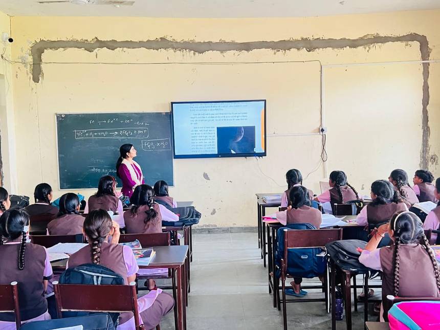A teacher taking a science lesson using the blackboard and smart class screen