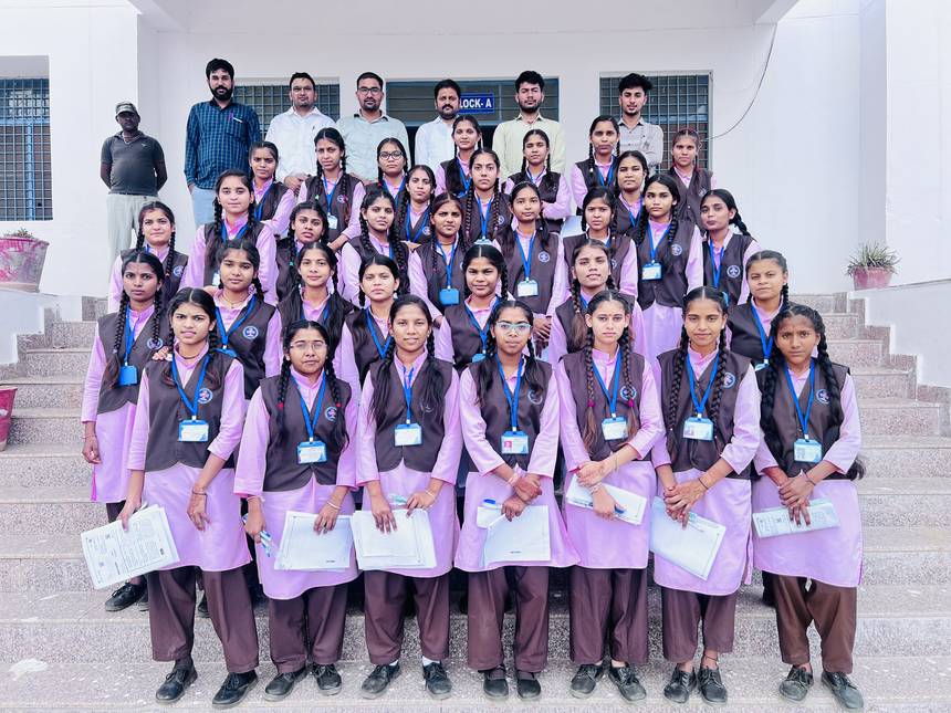 Students seated with staff on the steps of the Block A building entrance