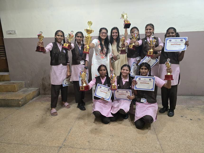 Students and teachers holding trophies and certificates won at a competition