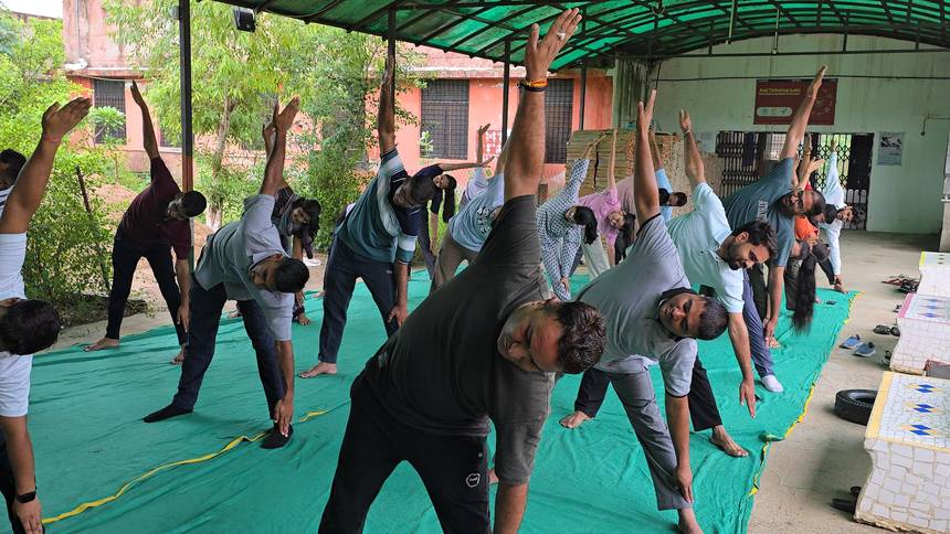 Staff and students performing a yoga stretch under the covered shelter